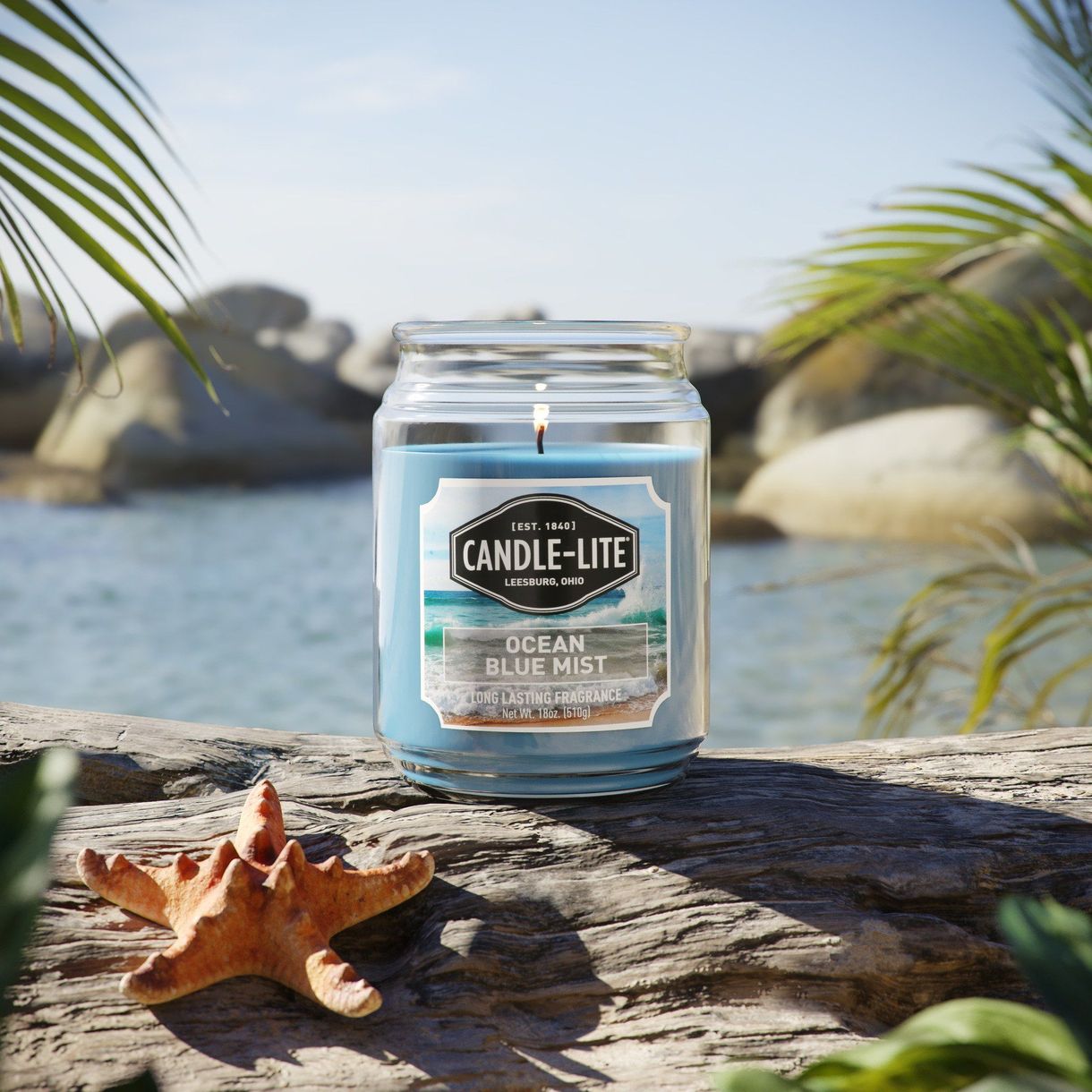 3D product rendering of Candle-Lite Ocean Blue Mist candle with beach background, showcasing photorealistic CGI visualization.