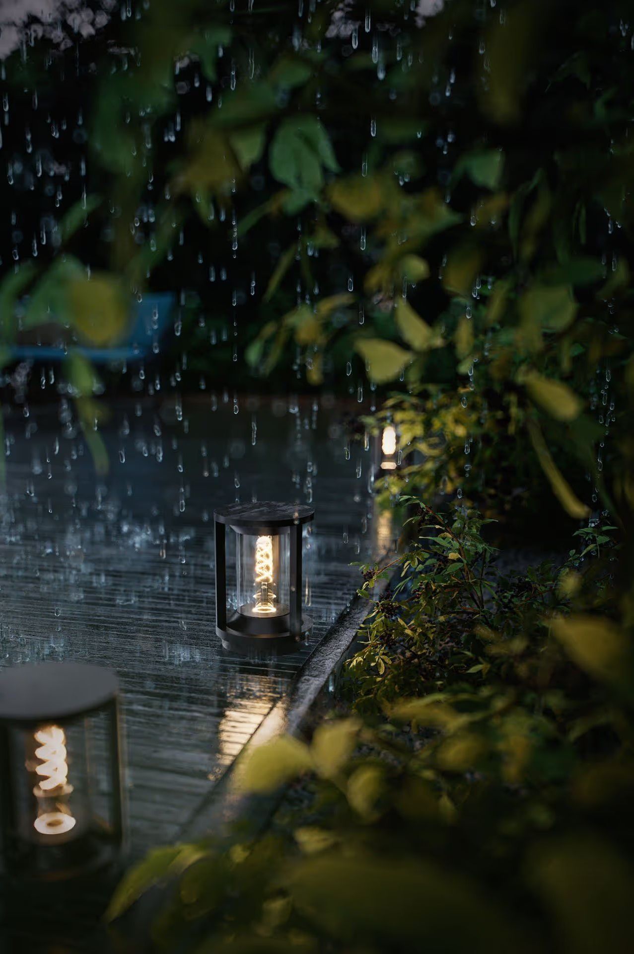 Outdoor pathway lights glowing in the rain along a garden edge at night shown in product rendering