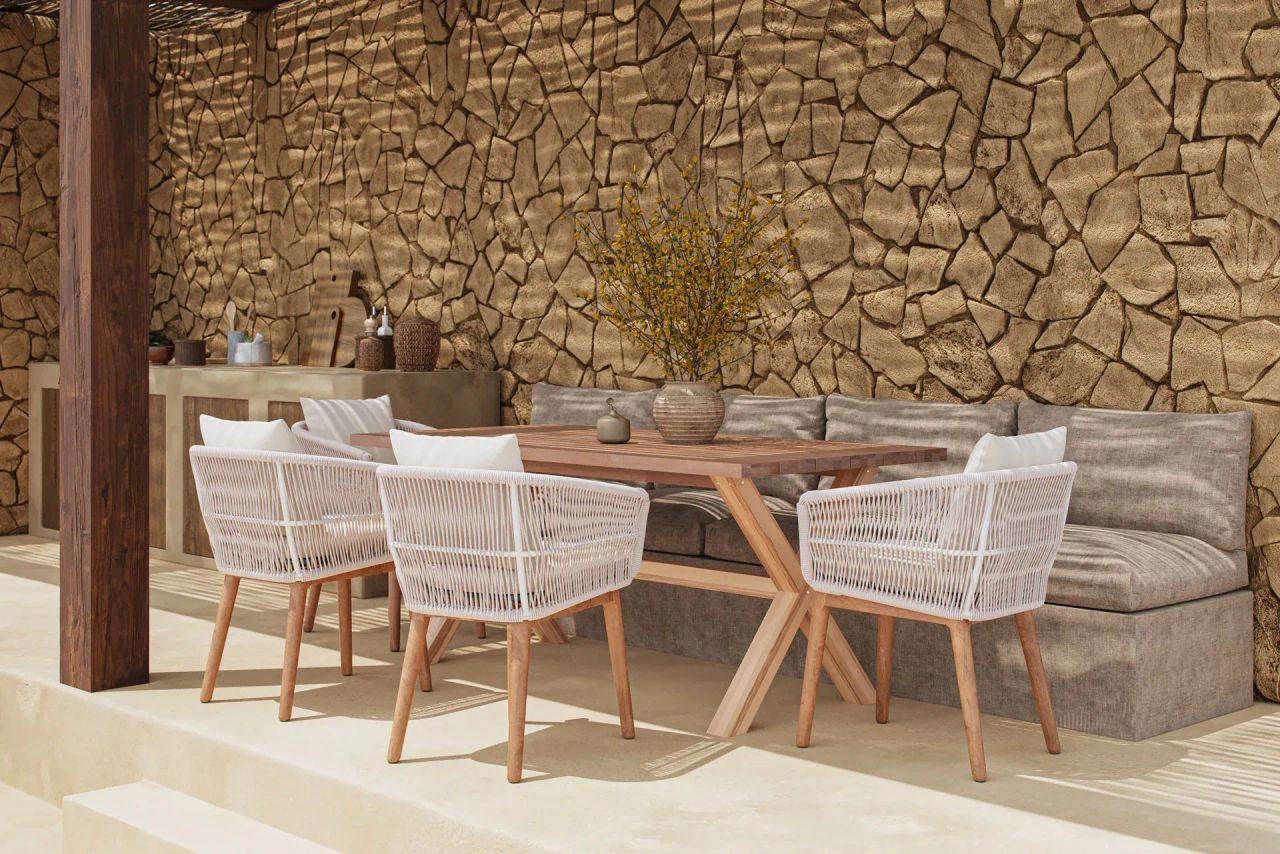 Product image for catalogs showing an outdoor poolside lounge with white chairs, wooden stools, and a stone wall backdrop