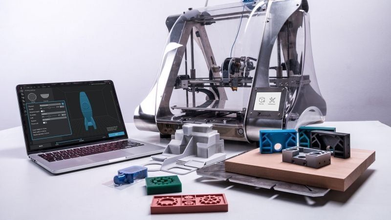 A 3D Printer with Printed Product 3D Models and a Laptop with the Design Project Open