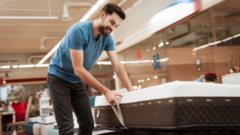 A Man Trying How Effective an Ottoman Bed Is During a Product Presentation