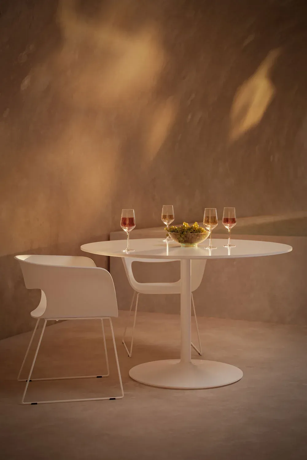 Product render for catalogs showing a round white dining table with modern chairs and wine glasses on top