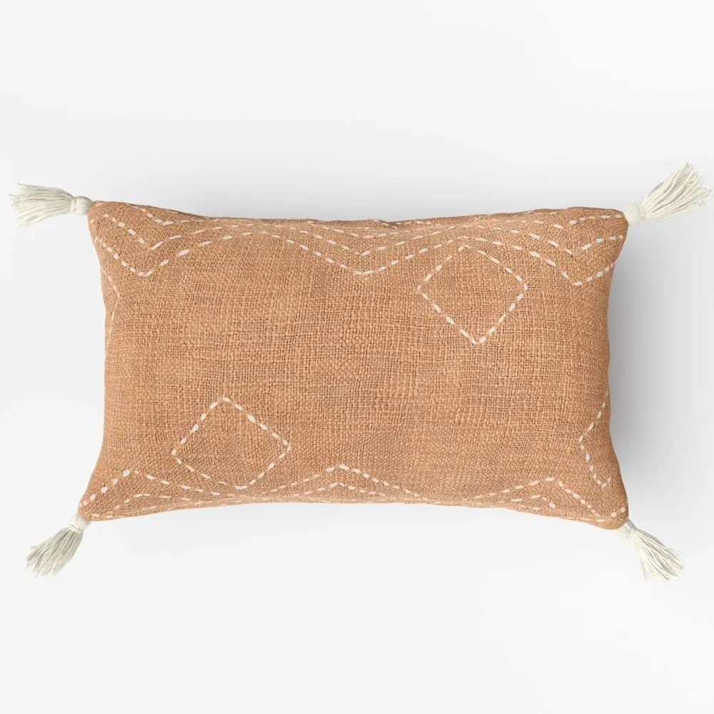 Product visualization for catalogs showing a brown pillow with stitched white geometric patterns and tassels