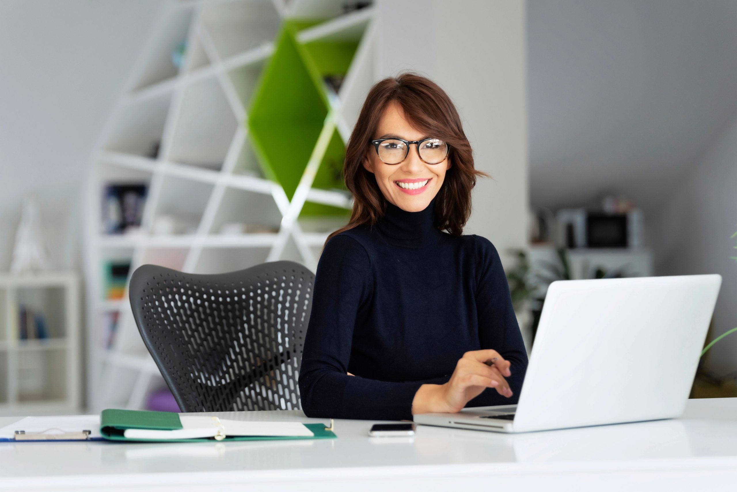 Marketing director working at a laptop in a modern office, planning campaigns for a furniture company
