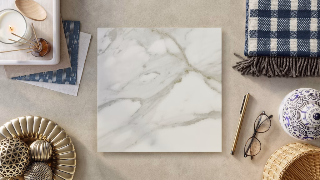 Flooring product rendering flatlay of Splendor Ivory marble-effect vinyl tile with gold accents, gingham textile, and blue-white ceramics
