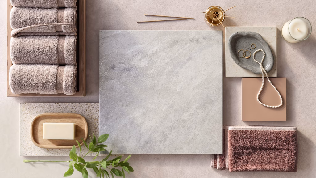 Flooring product rendering flatlay of Stone Heaven vinyl tile with towels, soap, pearls, and bathroom accessories in blush and grey tones