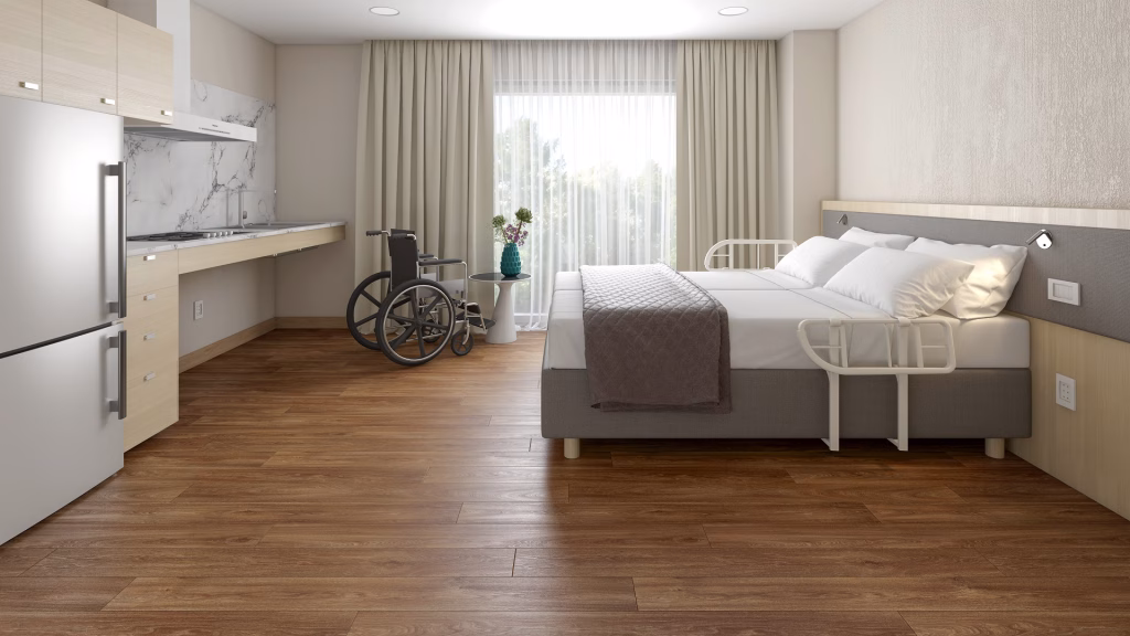Flooring product rendering of Xtreme Havanna Oak vinyl planks in a hospital room with a medical bed and wheelchair