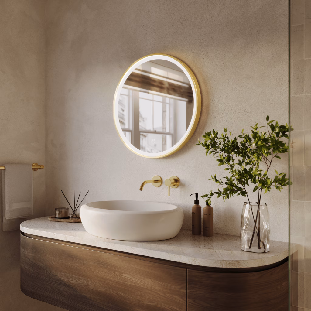 Angled 3D render of a small round gold-framed LED mirror above a vessel basin and brushed gold wall faucet