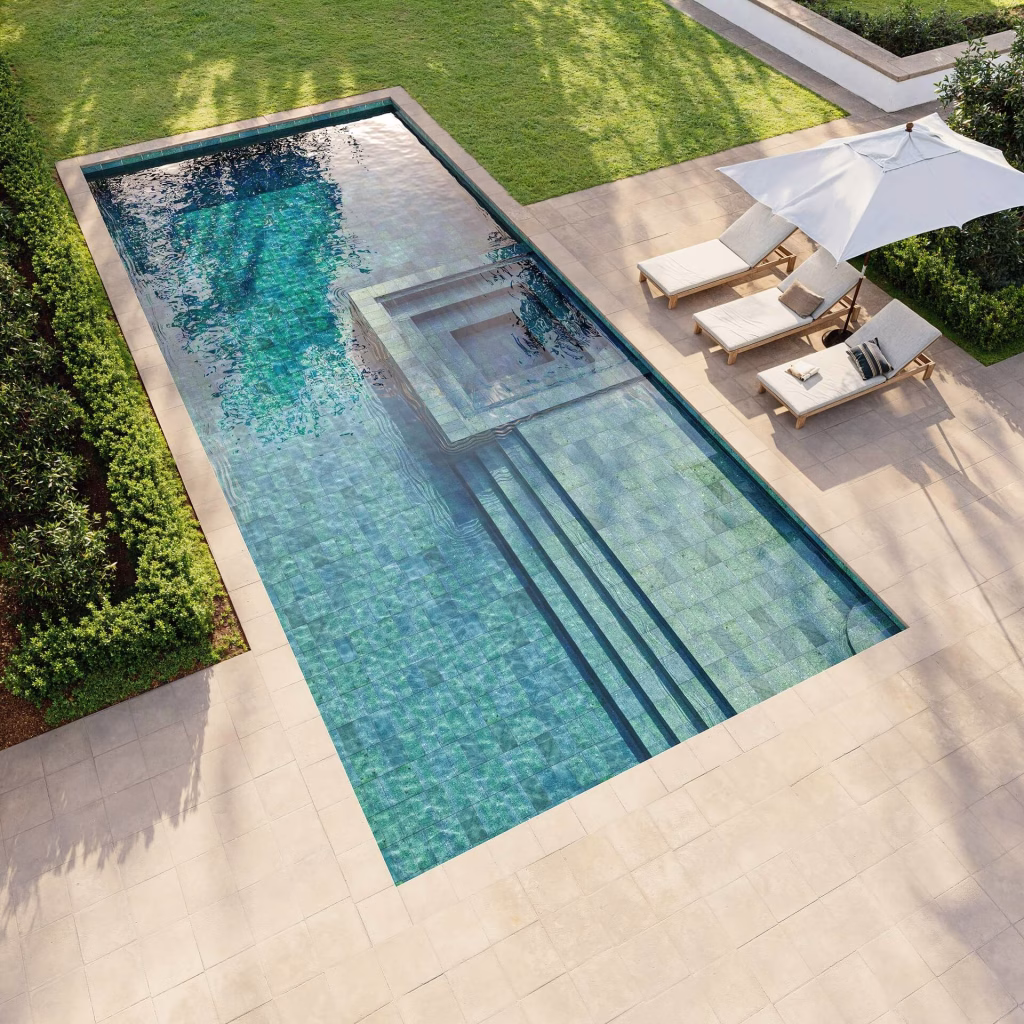 Aerial CGI view of a rectangular pool lined with green natural stone tile, with an inset spa, wide entry steps and loungers under an umbrella