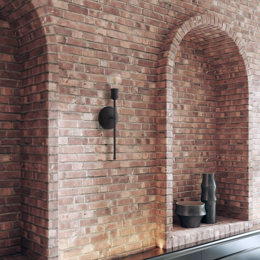 Close-up 3D rendering of a black Livex Lighting torch sconce on an exposed brick wall beside an arched niche